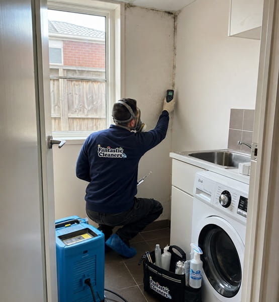 Fantastic Cleaners technician taking moisture readings on a mould-affected laundry wall corner